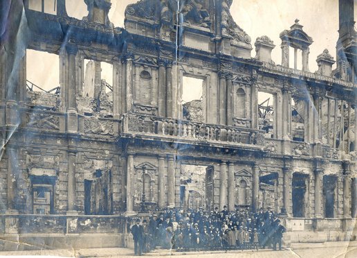 Groupe composé d'enfants, d'adolescents et d'adultes s'apprêtant à partir, entourés d'adultes, posant devant la façade détruite de l'hôtel de ville de Reims 